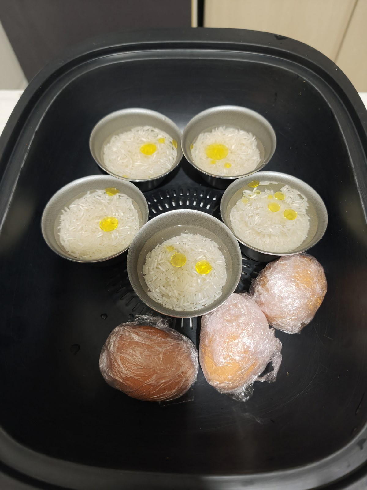 Vasitos de arroz y huevos envueltos en film en el recipiente Varoma